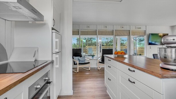 Eine moderne Küche mit weißen Schränken, einer Holz Arbeitsplatte und einem eingebauten Backofen.