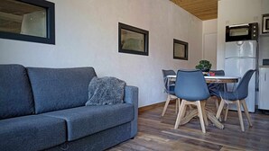 A modern living room with a grey sofa, a dining table with chairs, and a kitchen area with a microwave and refrigerator. - ❤LA GRANGE SAVOYARDE⭐⭐⭐Lac 1KM-💦Pool-Charm (Lathuile)