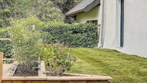 A wooden house with a sloped roof and a small garden area with a wooden fence and plants. - ❤LA GRANGE SAVOYARDE⭐⭐⭐Lac 1KM-💦Pool-Charm (Lathuile)