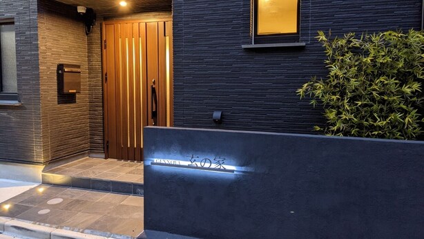 A modern building entrance with a wooden door, a small window, and a well-lit sign. - Gennoya (Tokyo)
