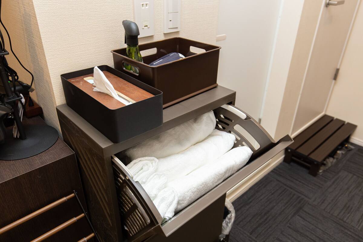 Une chambre d’hôtel équipée d’un bureau, d’un tiroir contenant des serviettes, d’une bouteille et d’une boîte.