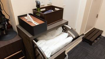 Une chambre d’hôtel équipée d’un bureau, d’un tiroir contenant des serviettes, d’une bouteille et d’une boîte.