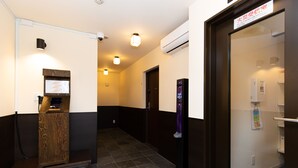 A hotel hallway with a wooden reception desk, a vending machine, and an air conditioning unit. - Gennoya (Tokyo)