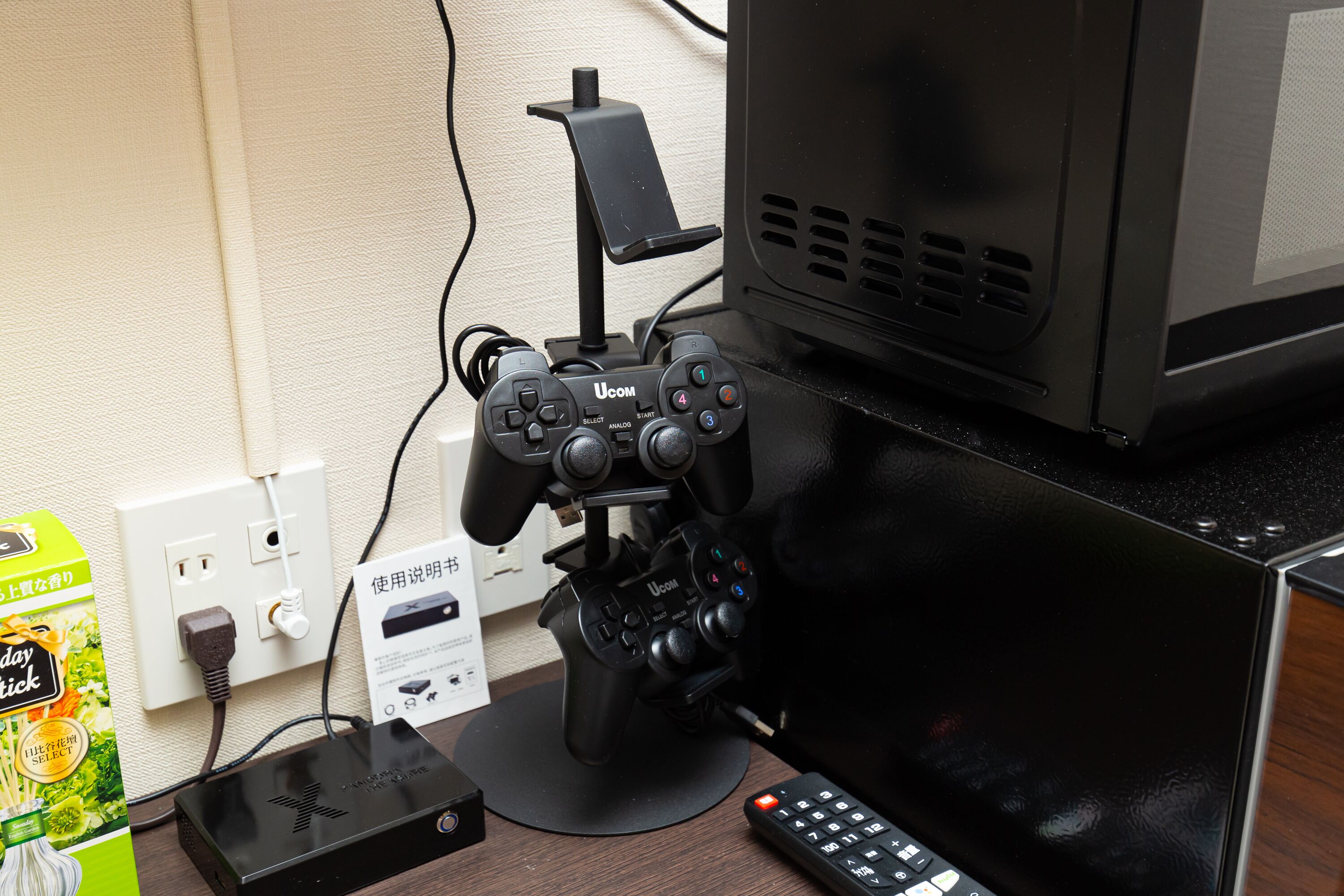 Una configuración para jugar videojuegos con una consola UCOM, un control, un monitor y un control remoto sobre un escritorio.