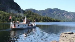 A boat named 'Bjoren' on a calm lake with mountains in the background. - Dølen Hotel (Evje)