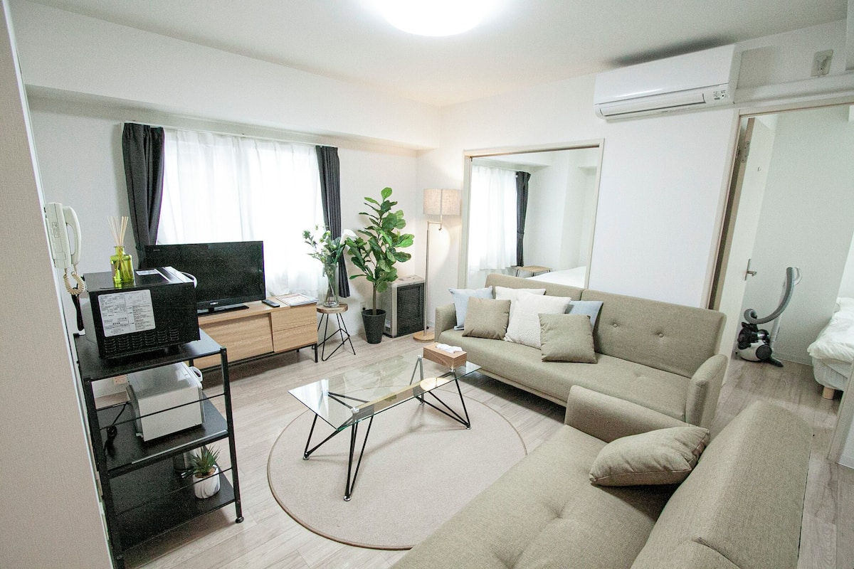 A modern living room with a sofa, TV, and a glass coffee table.