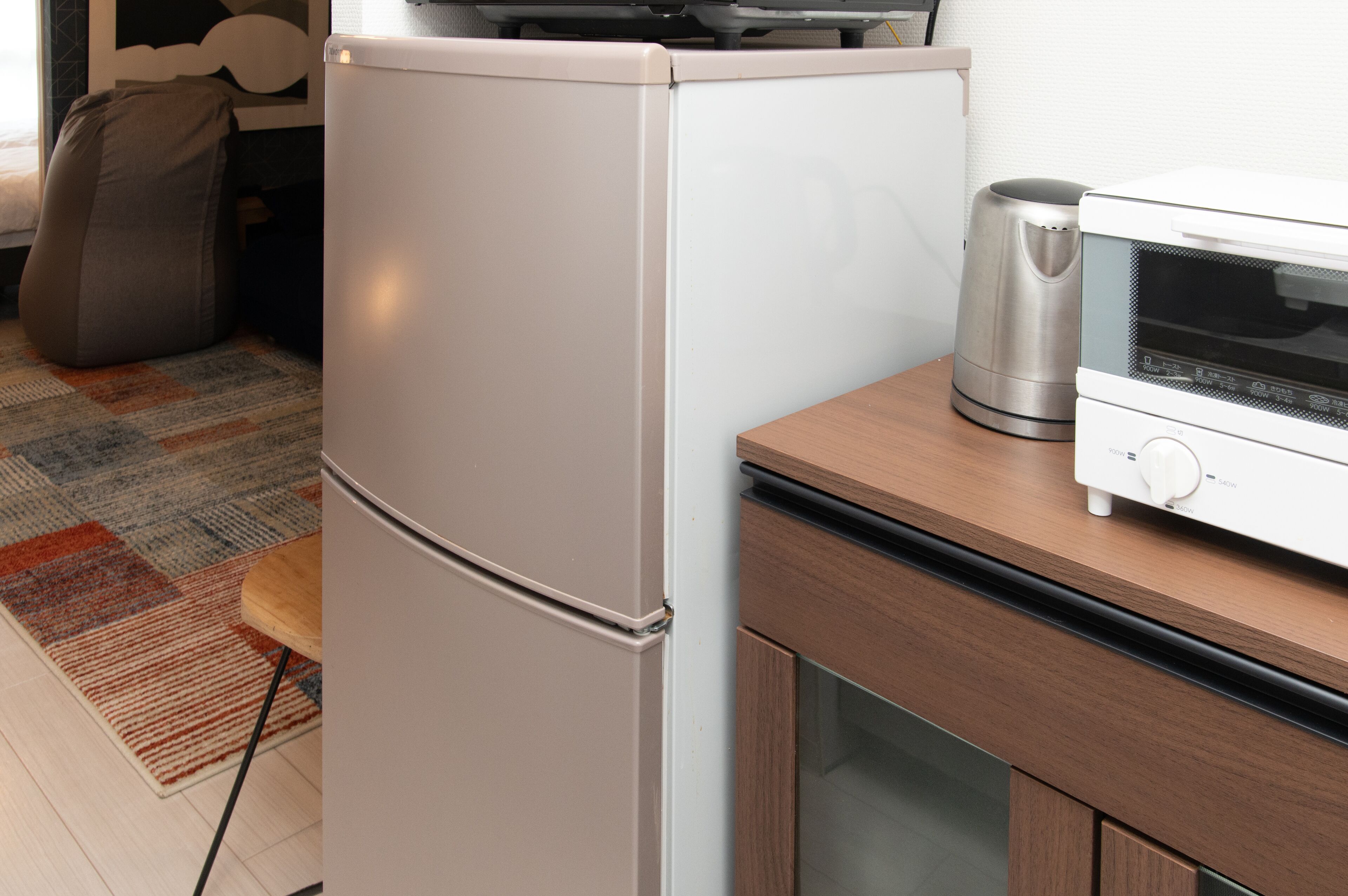 Una cucina compatta con frigorifero, forno a microonde e bollitore sul piano di lavoro.