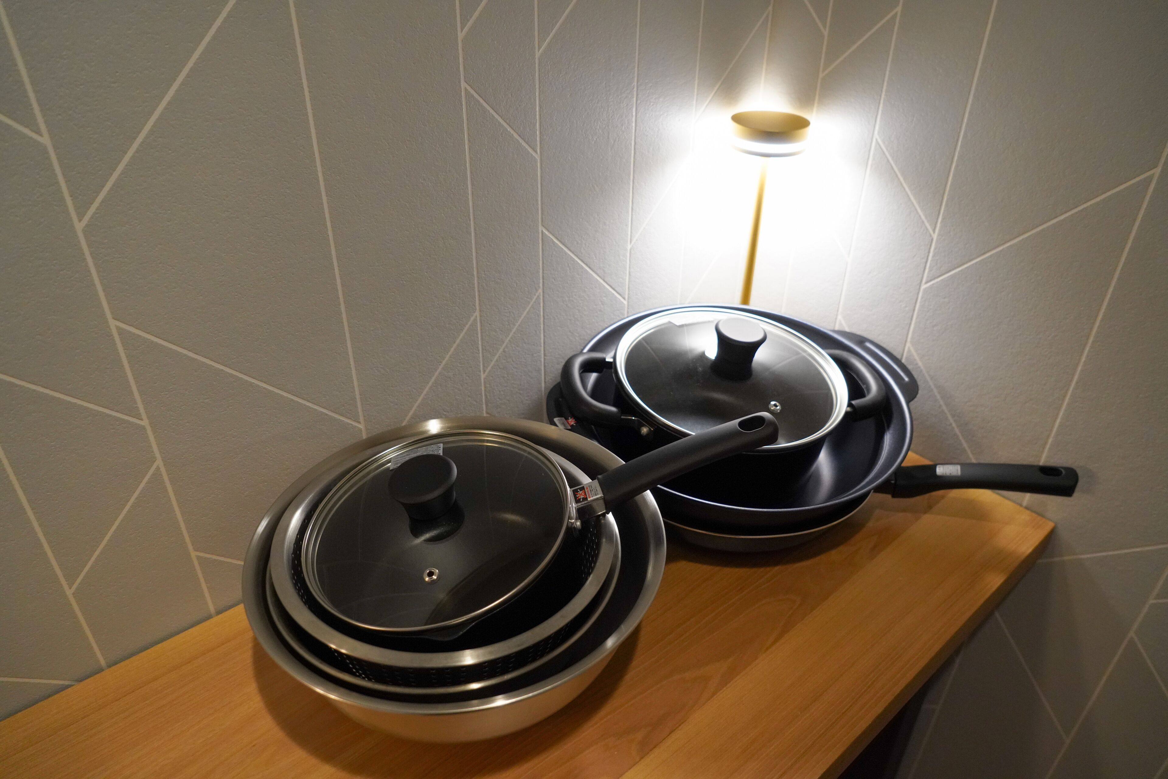 Two electric skillets on a wooden countertop with a modern tiled backsplash.