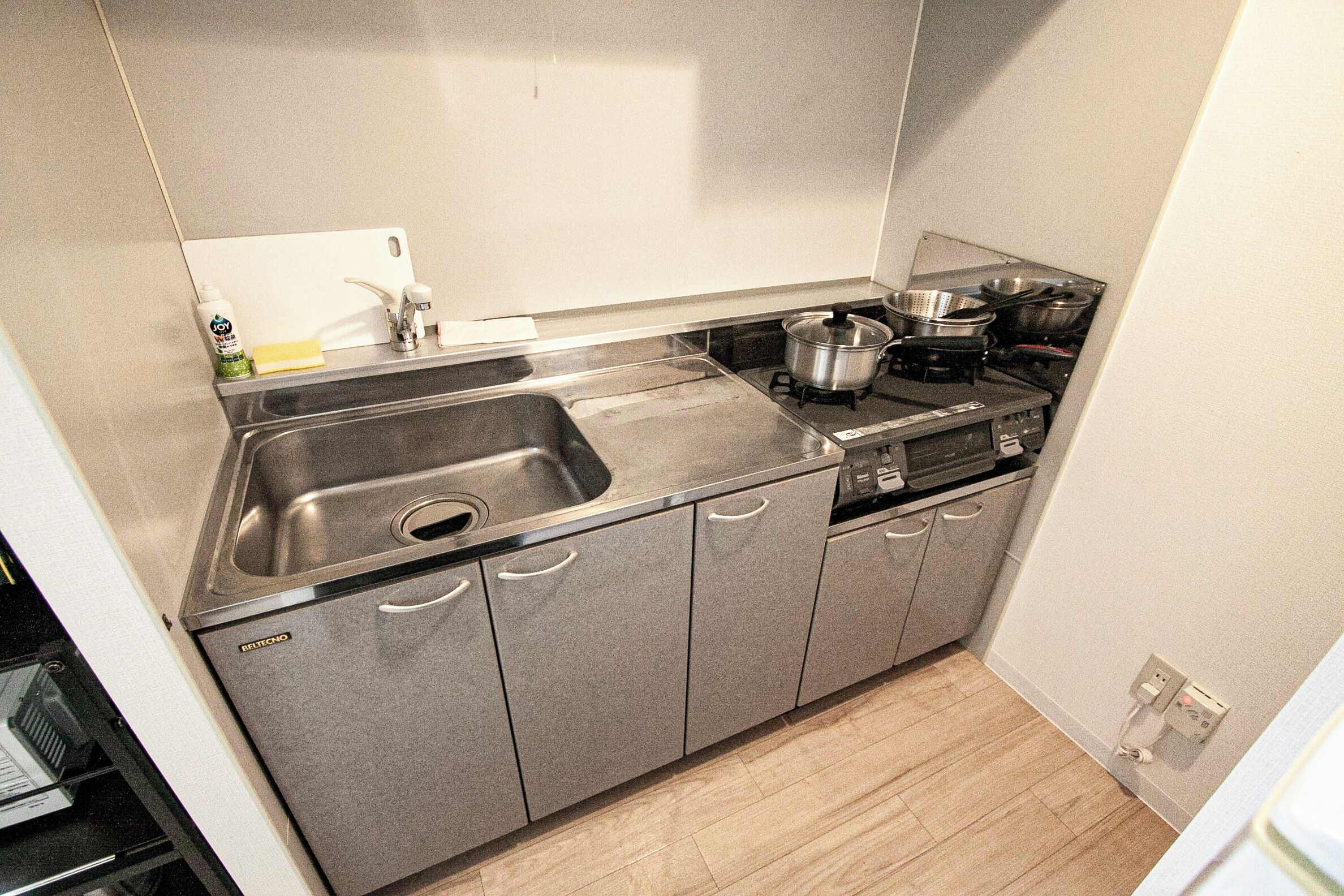 Ett kök med en diskho i rostfritt stål, en spis och en diskmaskin.