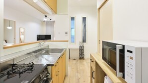 A compact kitchen with a gas stove, stainless steel sink, and a microwave.