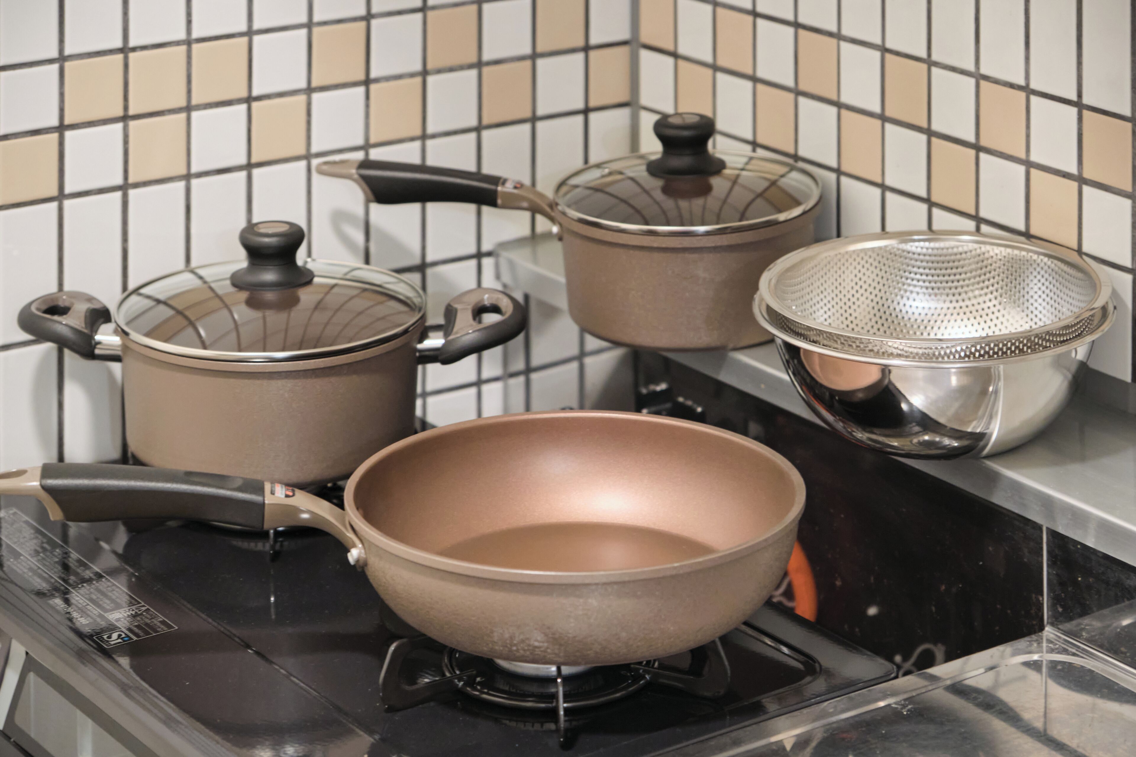 Una cocina con estufa, ollas y un colador.