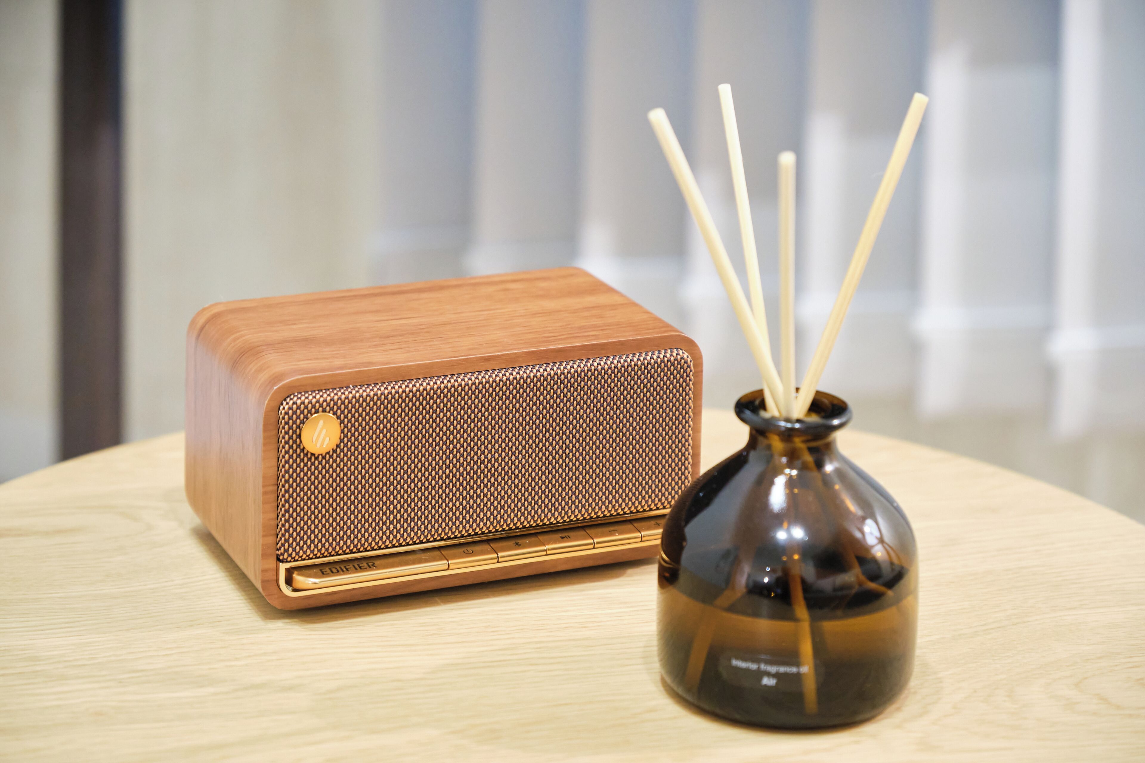 A vintage radio and a vase with reed diffusers on a wooden table.