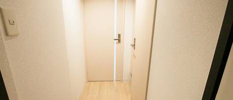 Un pasillo estrecho con suelo de madera y una puerta al final.