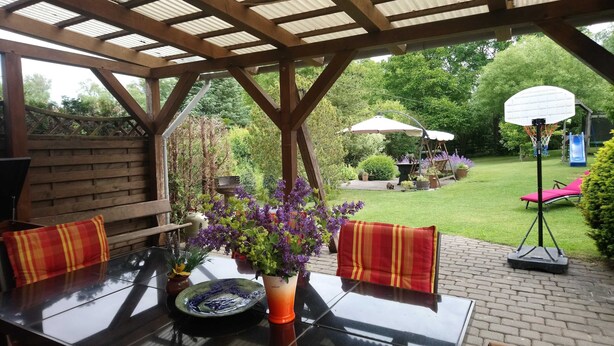 An outdoor patio with a table, chairs, and a pergola structure. - Ferienwohnung Teschow (Teterow)