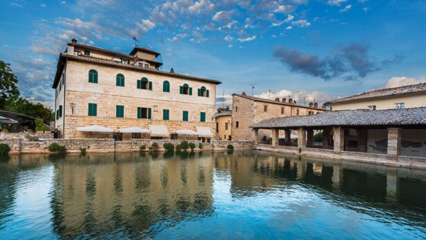 A stone building with a courtyard and a canal. - Palazzo Brandano (Trequanda)
