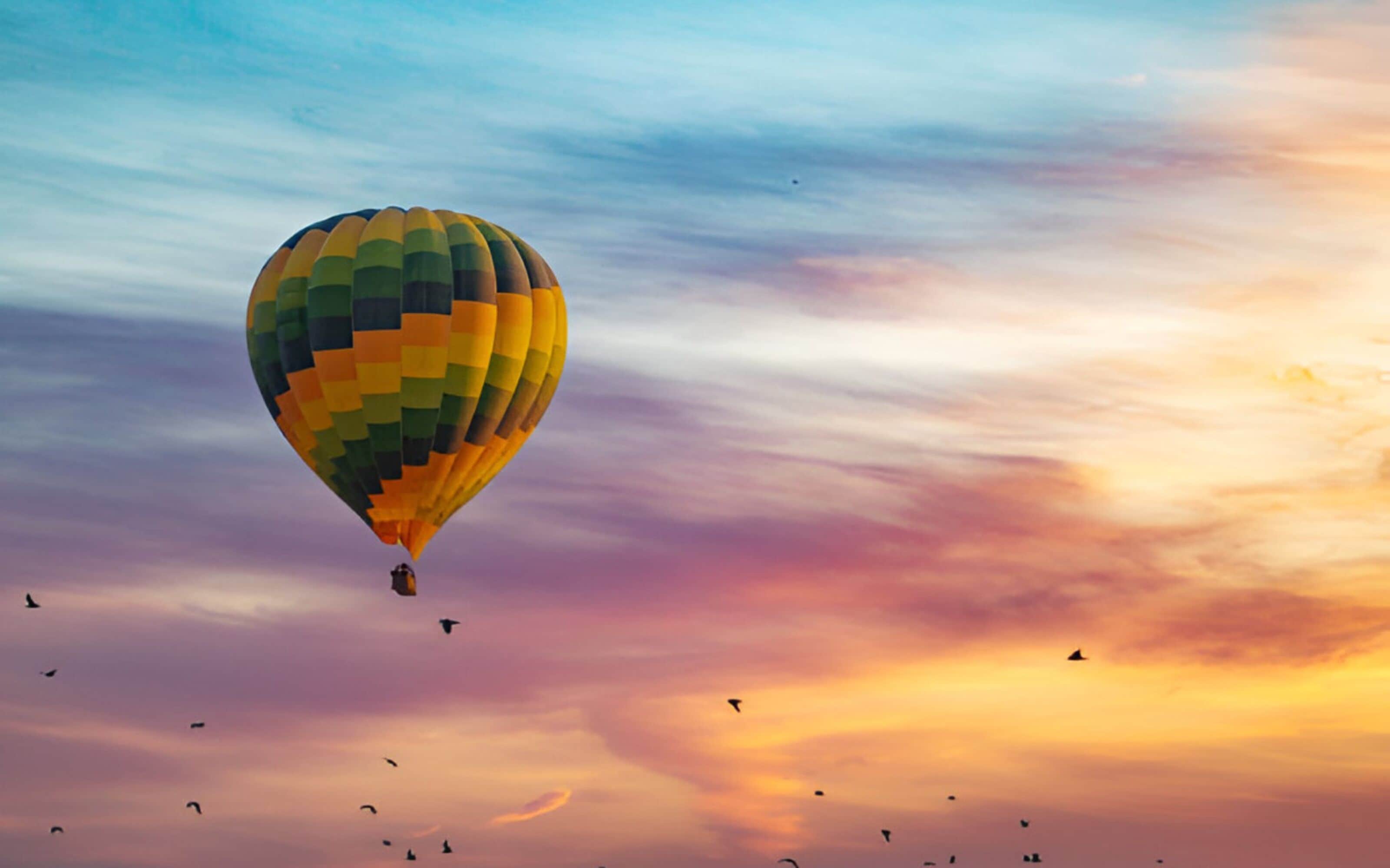 A hot air balloon with a colorful pattern against a sunset sky.