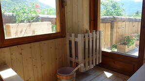 A wooden cabin interior with a wooden deck outside, a wooden bucket, and a wooden door. - Studio With Panoramic View (Gignod)