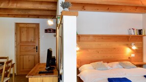 A wooden-framed room with a bed, a desk with a computer, and a door. - Studio With Panoramic View (Gignod)