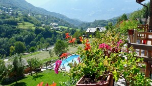 A balcony with a view of a mountainous landscape, a swimming pool, and potted plants. - Studio With Panoramic View (Gignod)