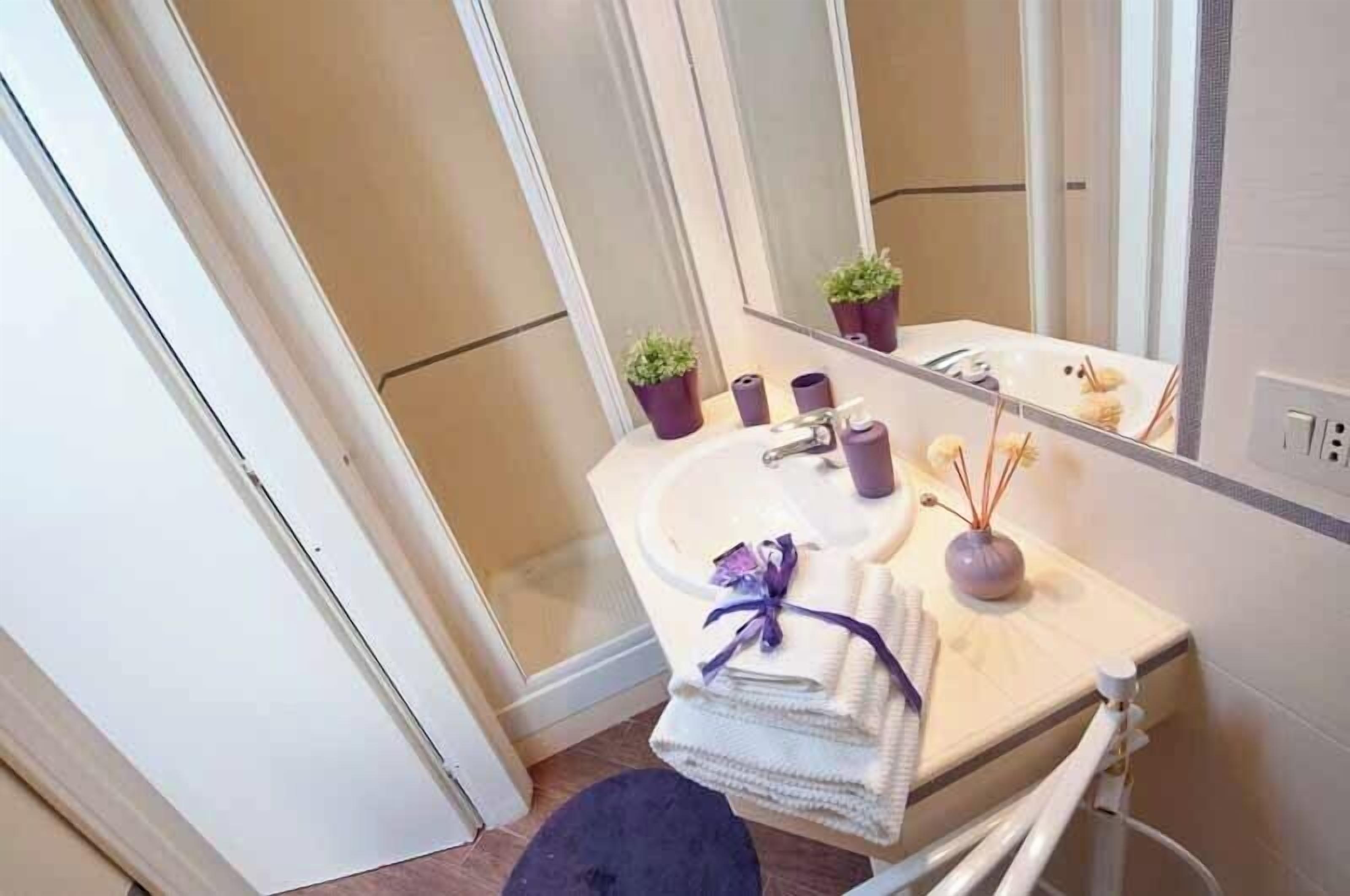 A bathroom with a sink, mirror, and two potted plants.