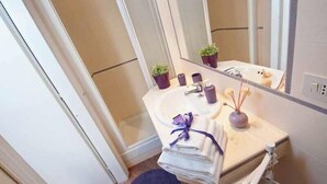 Een badkamer met een wastafel, spiegel en twee potplanten.