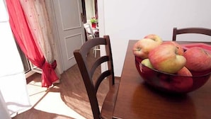 A dining table with a bowl of apples and a red curtain. - Confortevole Appartamento Vicinissimo al Vaticano, Metro, AC & Fast Wifi (Rome)