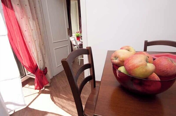 Una mesa de comedor con un cuenco de manzanas y una cortina roja.
