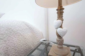 A bedside table with a lamp featuring a decorative base and heart-shaped lampshades. - Confortevole Appartamento Vicinissimo al Vaticano, Metro, AC & Fast Wifi (Rome)