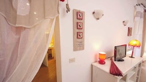 A room with a white console table, a red lamp, and a wall-mounted shelf. - Confortevole Appartamento Vicinissimo al Vaticano, Metro, AC & Fast Wifi (Rome)