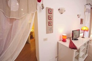 A room with a white console table, a red lamp, and a wall-mounted shelf.