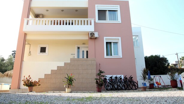 A two-story building with a balcony, a staircase, and a row of bicycles parked outside.