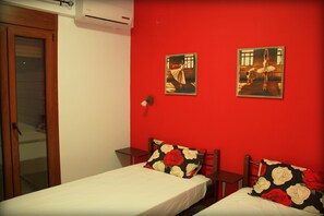 A room with two beds, red walls, and two paintings of dancers.