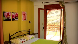 Une chambre à coucher avec un lit, une fenêtre donnant sur un jardin et une porte.