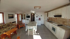 Un ambiente compatto con angolo ristoro, angolo cottura e divano.