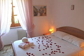 A neatly made bed with rose petals, a rolled towel, and a painting on the wall. - Villa La Favola Suite Ischia Terrace With View (Barano d'Ischia)