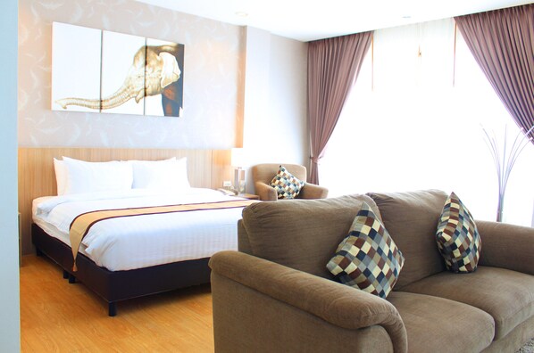 A hotel room with a bed, a sofa, and a painting on the wall.