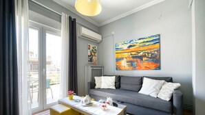 A modern living room with a grey sofa, a wooden coffee table, and a painting on the wall. - 1 Bedroom Superior Apartment (Athens)