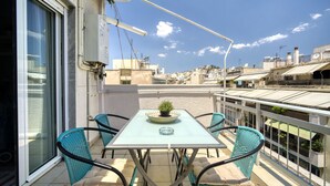 A balcony with a table and chairs, a potted plant, and a view of the cityscape. - 1 Bedroom Superior Apartment (Athens)