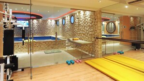 Ett gym med träningsutrustning, en massagebänk och en gul träningsmatta.