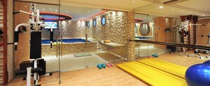 A gym with exercise equipment, a massage table, and a yellow exercise mat.