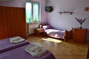 A bedroom with two beds, a television, a small cabinet, and a window with curtains. - B b S Elia Villa Surrounded by Greenery Inside the Historic Dubini Park (San Cataldo)
