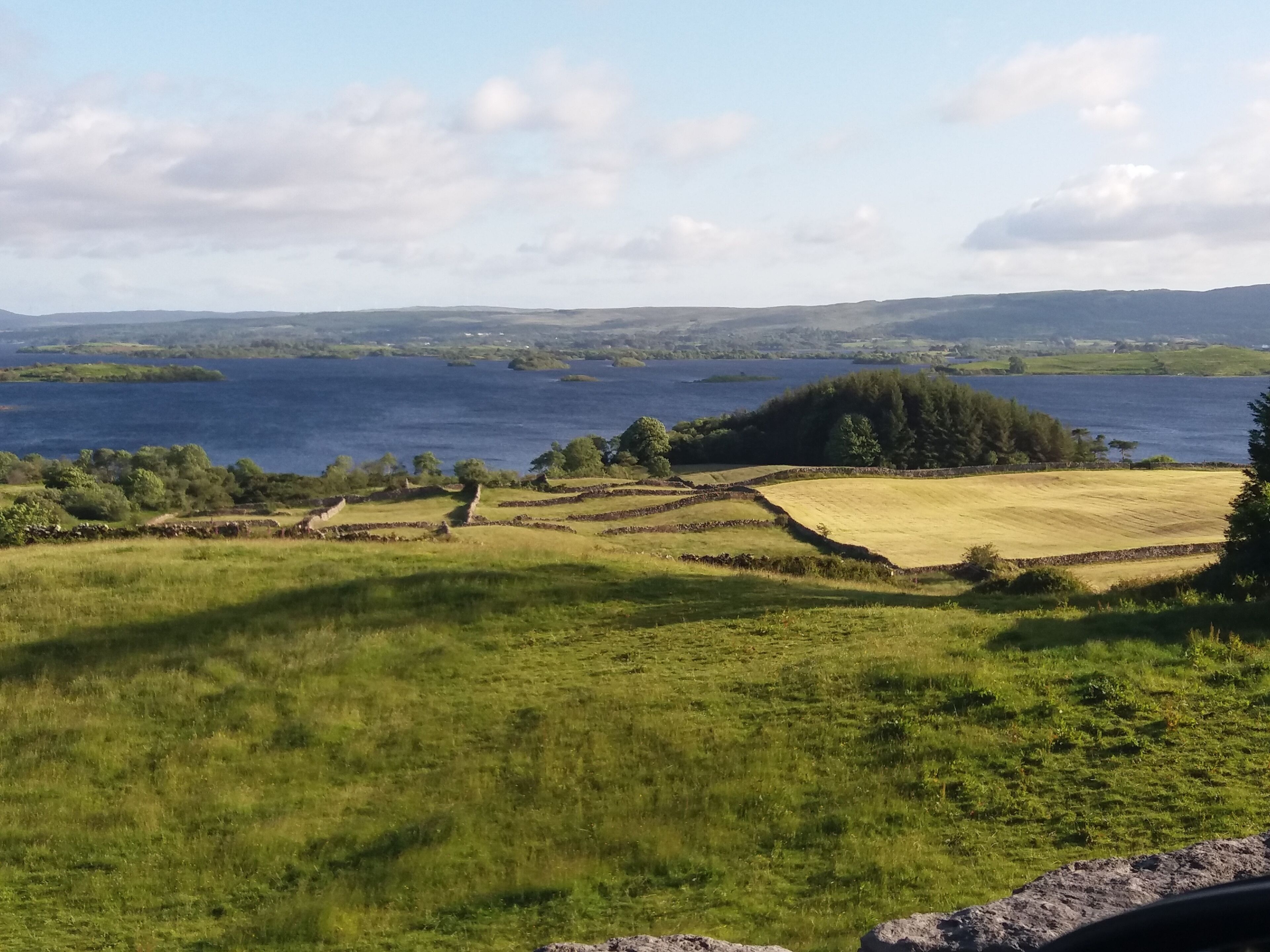 A rural landscape with fields, a lake, and distant hills.
