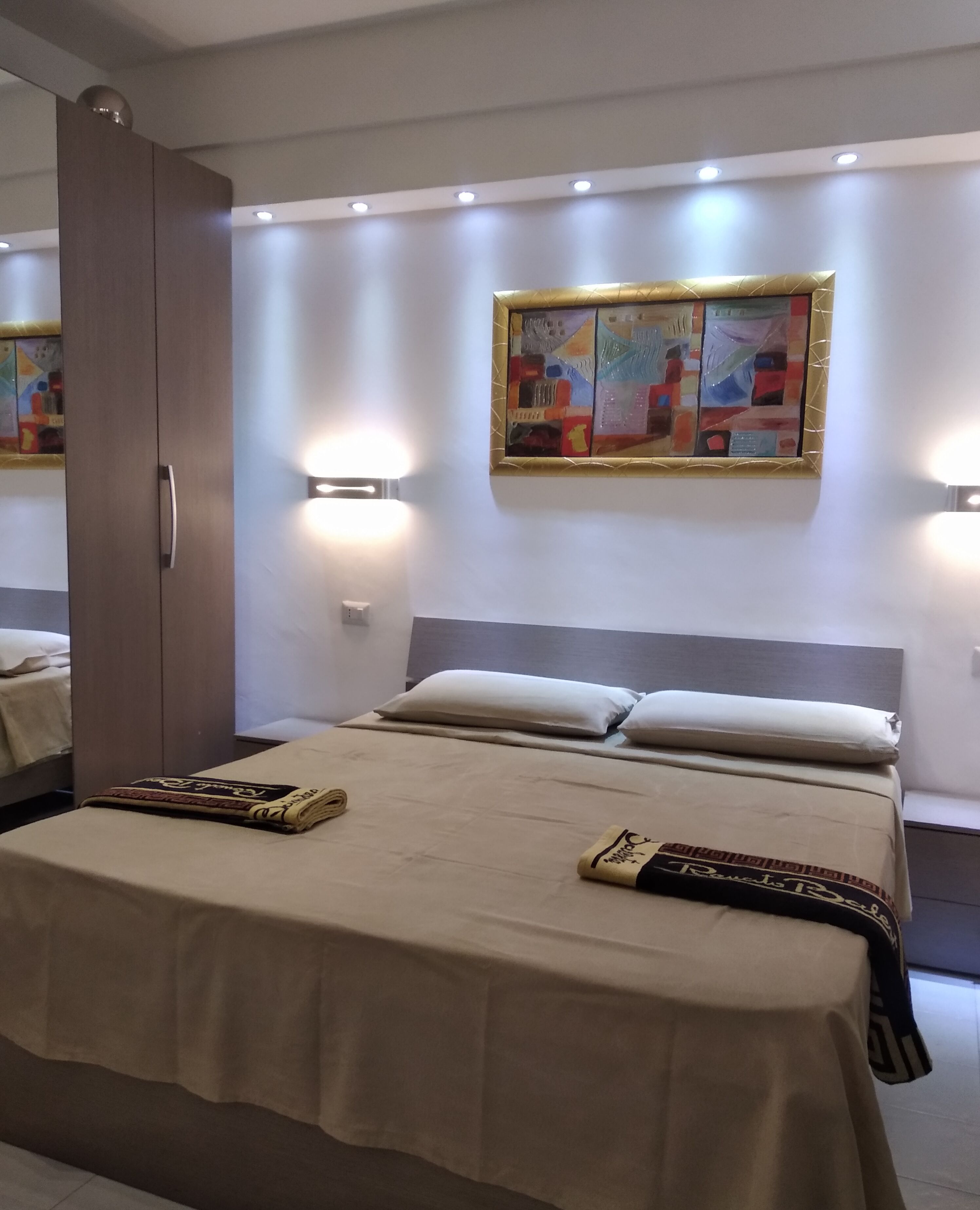 Une chambre d’hôtel moderne avec un grand lit, une armoire et un tableau au mur.