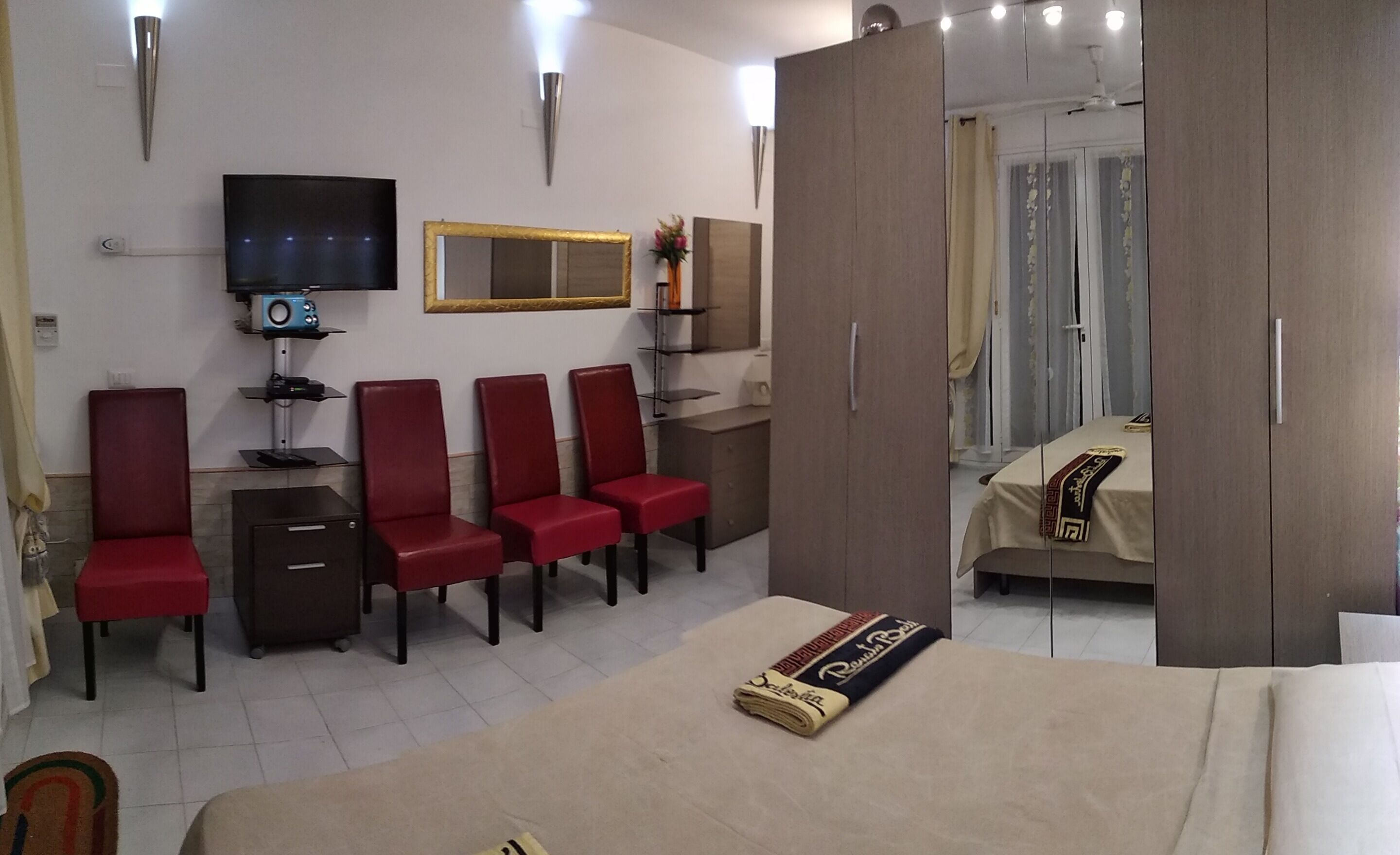 Una camera d'albergo con un letto, una televisione, una scrivania e un armadio.
