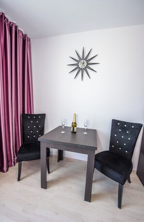 A room with a table and two chairs, a bottle of champagne, and a wall clock. - Tower Studio Peaceful Studio With Panoramic View Next to Cișmigiu Gardens (Bucharest)