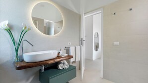 A modern bathroom with a large oval mirror, a wooden vanity, a white sink, and a built-in shower. - Villa Marianna Like Paradise in Amalfi Coast!!! (Massa Lubrense)