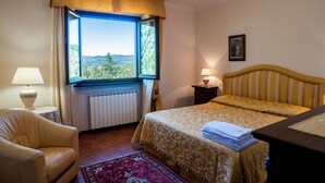 A bedroom with a bed, a chair, a window with a view, a radiator, and a lamp. - Wonderful Villa With Private Pool in the Heart of Tuscany (Pratovecchio Stia)