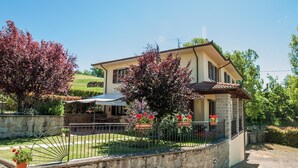A two-story house with a stone facade, a patio with a table and chairs, and a garden with flowering plants. - Wonderful Villa With Private Pool in the Heart of Tuscany (Pratovecchio Stia)