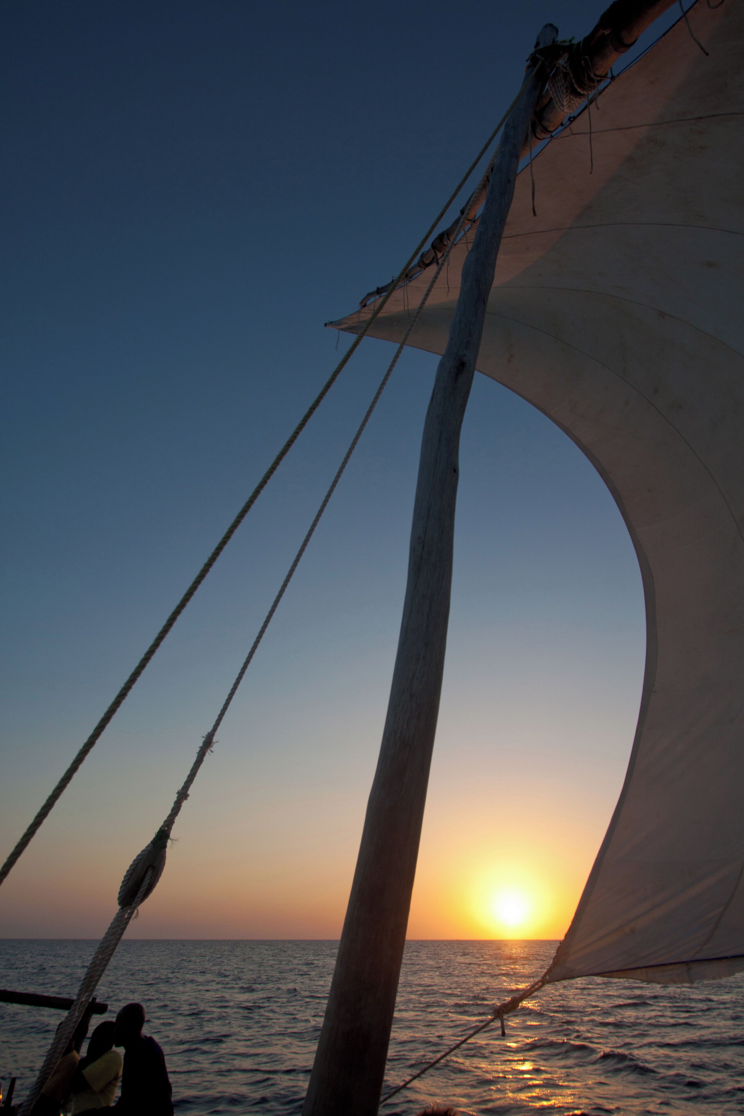 A sailboat with a large sail and a person at the stern.