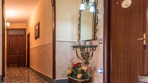 A hallway with a wooden door, a wall-mounted mirror, and a flower basket. - Bb La Mortella With Pool (Roccadaspide)